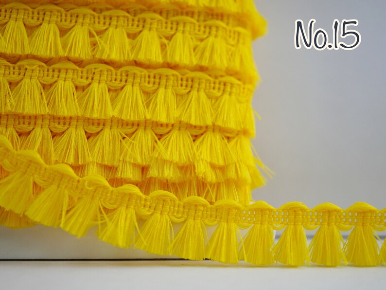 May include: Yellow tassel trim with a scalloped edge. The trim is approximately 2.5 cm wide and has a fringe length of about 2.5 cm. No. 15