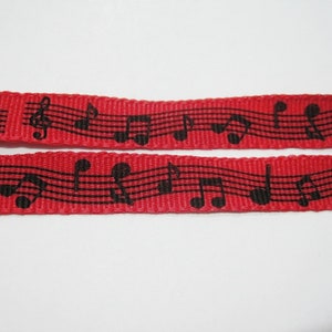 May include: Red ribbon with black musical notes printed on it. The ribbon is woven and has a textured surface.