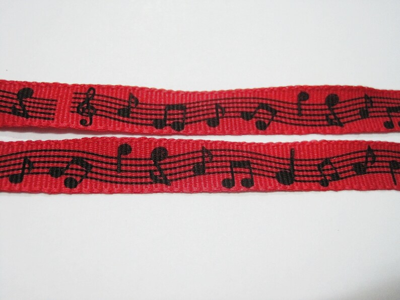 May include: Red ribbon with black musical notes printed on it. The ribbon is woven and has a textured surface.