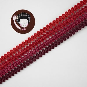 May include: Red, pink and burgundy ombre trim with a scalloped edge. The trim is made of a soft, woven fabric.