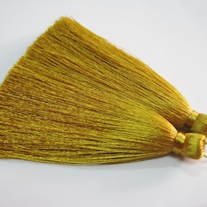 May include: Two gold silk tassels with a metallic gold loop at the end. The tassels are approximately 7.5 cm long.