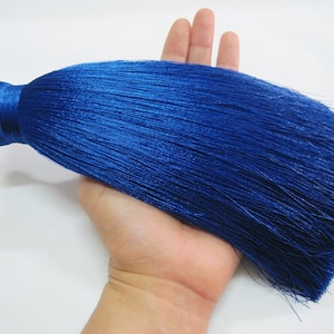 Peut inclure: Un long pompon bleu foncé avec un sommet arrondi. Le pompon est fait de fils doux et soyeux et mesure environ 25 cm de long.