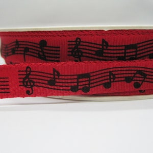 May include: Red ribbon with black musical notes printed on it.