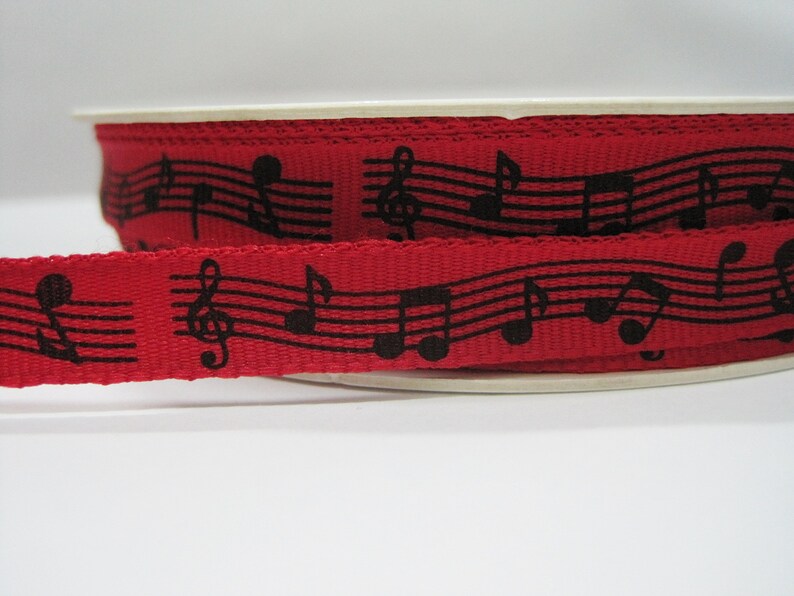 May include: Red ribbon with black musical notes printed on it.