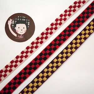 May include: Three checkered ribbons in red and white, red and black, and brown and gold. The ribbons are arranged diagonally on a white background.