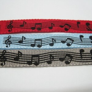 May include: Three different colored ribbons with a black musical note pattern. The ribbons are red, light blue, and gray.