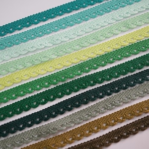 May include: Assortment of green, blue, and brown scalloped trim ribbon. The ribbon is arranged in a gradient pattern.