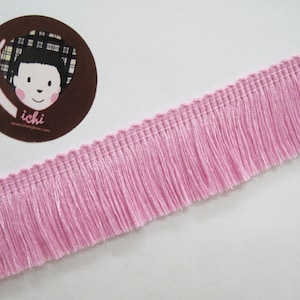 May include: Pink fringe trim with a scalloped edge. The fringe is approximately 2.5 cm long.
