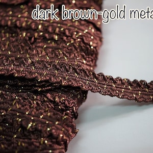 May include: Dark brown metallic trim with gold accents. The trim has a textured, ruffled design and the text "dark brown-gold metallic" is visible in the image. This decorative trim is suitable for various craft projects.