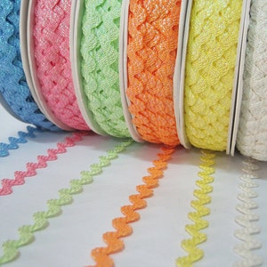 May include: A set of six spools of decorative trim with a zig-zag pattern. The trim is available in blue, pink, green, orange, yellow, and white.