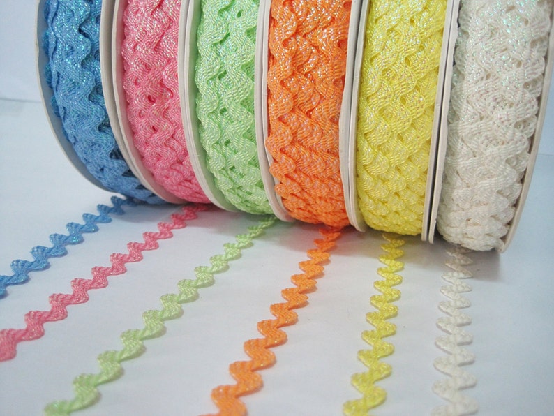 May include: A set of six spools of decorative trim with a zig-zag pattern. The trim is available in blue, pink, green, orange, yellow, and white.