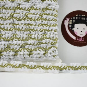 Op de afbeelding: Witte en olijfgroene elastische trim met een gekrulde rand. De trim is gemaakt van een zacht, rekbaar materiaal en is perfect om een ​​toets van elegantie aan elk project toe te voegen.
