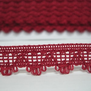May include: Red crocheted trim with a delicate, intricate pattern. The trim features a scalloped edge and a repeating design of small loops and squares.
