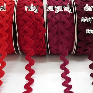 Puede incluir: Cuatro carretes de ribete decorativo de ric-rac en tonos rojo, rubí, burdeos y rojo escarlata oscuro. Cada carrete está etiquetado con el nombre de su color. El ribete tiene un diseño ondulado en zigzag.