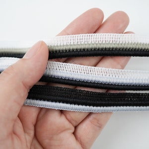 May include: Three different types of black, white and grey elastic trim with a textured weave.