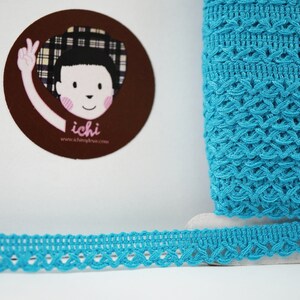 May include: Turquoise blue crochet trim with a delicate, intricate pattern. The trim is shown rolled up and laid flat.