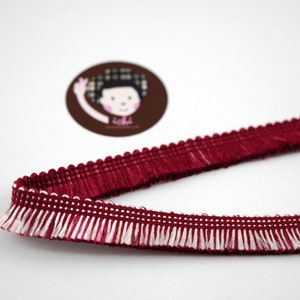 May include: Burgundy and white trim fringe trim with a scalloped edge.