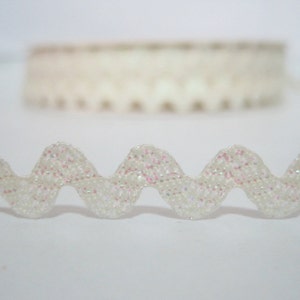 May include: White scalloped trim with iridescent glitter. The trim is wavy and has a delicate, feminine look.