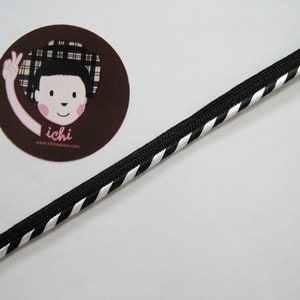 May include: Black and white striped trim with a white background and black stripes. The trim is made of a soft, flexible material.