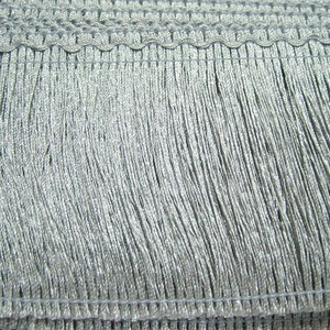 May include: Silver fringe trim with a woven edge. The fringe is approximately 2.5 cm long.