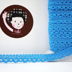 May include: A roll of bright blue crochet trim with a delicate, intricate pattern. The trim is approximately 1 inch wide.