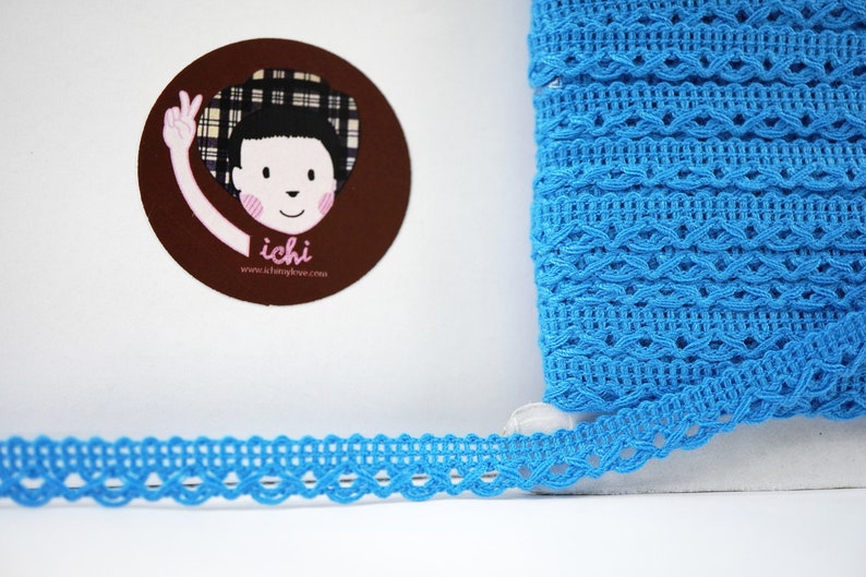 May include: A roll of bright blue crochet trim with a delicate, intricate pattern. The trim is approximately 1 inch wide.