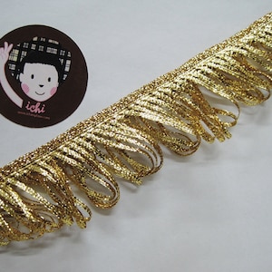 May include: Gold metallic fringe trim with a subtle shimmer. The fringe is approximately 1 inch in length.