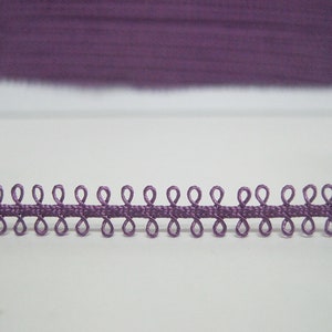 Op de afbeelding: Paarse elastische trim met een reeks kleine lussen. De trim is ongeveer 1,2 cm breed.