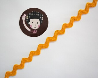 May include: A bright yellow zig zag trim with a small, round sticker featuring a cartoon character with the text "ichi" and a website address.