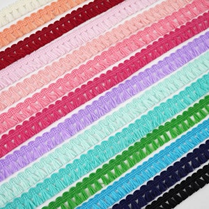 May include: A selection of colourful tassel trim with a scalloped edge. The trim is made from soft, fluffy yarn and is ideal for adding a touch of whimsy to any project.