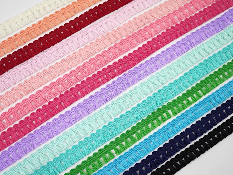 May include: A selection of colourful tassel trim with a scalloped edge. The trim is made from soft, fluffy yarn and is ideal for adding a touch of whimsy to any project.