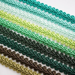 Puede incluir: Filas de adornos decorativos en varios tonos de verde, de claro a oscuro. El adorno tiene un borde festoneado en bucle, creando un diseño texturizado y estampado. Ideal para proyectos de costura y manualidades.