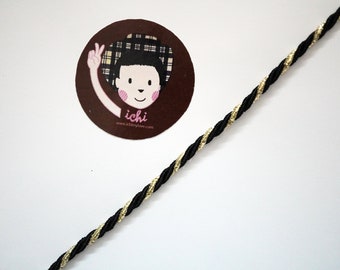 May include: Black and gold twisted cord with a brown circle sticker featuring a cartoon character with a plaid hat and the text "ichi" and "www.ichimylove.com".