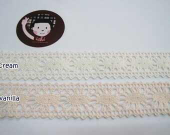 May include: Two samples of lace trim, one in cream and one in vanilla. The lace has a delicate floral pattern.
