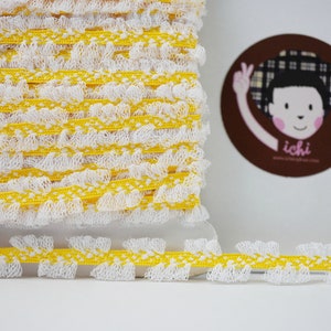 Op de afbeelding: Gele en witte elastische trim met een gerimpelde rand. De trim is gemaakt van een zacht, rekbaar materiaal en is perfect om een ​​toets van whimsy toe te voegen aan elk project.