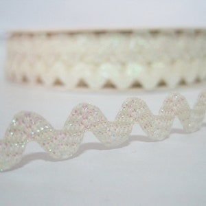 May include: White iridescent glitter trim with a wavy edge. The trim is rolled up on a spool.