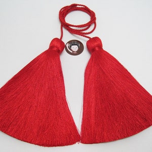 May include: Two red silk tassels with a long red cord. The tassels are approximately 7.5 cm in length.
