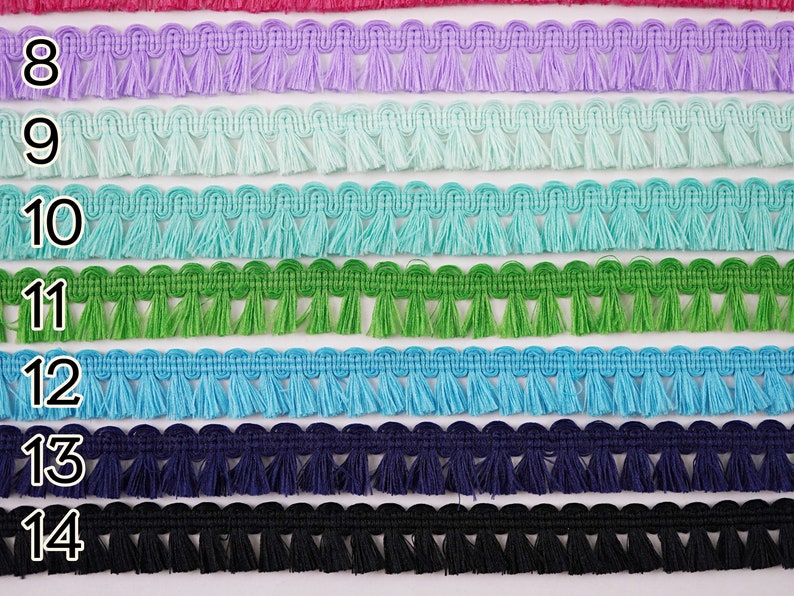 May include: A close-up of eight rows of fringe trim in various colours, including lavender, light blue, turquoise, green, blue, navy, and black. The trim is numbered 8 through 14.