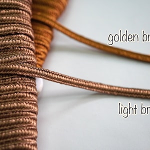 May include: Two spools of cord, one light brown and one golden brown. The cords are twisted and have a textured surface.