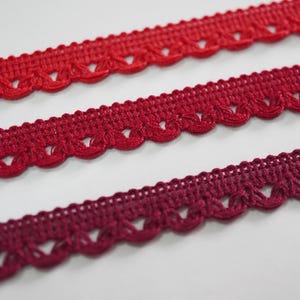 May include: Three pieces of red and burgundy crochet trim with scalloped edges.