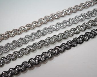 Può includere: Quattro diversi colori di bordino ondulato con una finitura scintillante. Il bordino è argento, nero, grigio e beige.