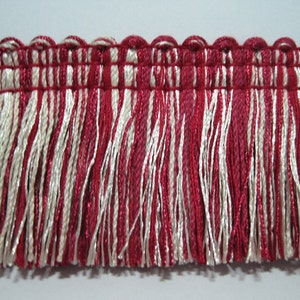 May include: Red and white fringe trim with a woven top edge. The fringe is made of thin, twisted threads.