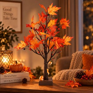 May include: A decorative tabletop tree featuring dark brown branches adorned with vibrant orange, red, and yellow maple leaves, small black and red berries, and two small squirrel figurines attached to the trunk, set on a square base.