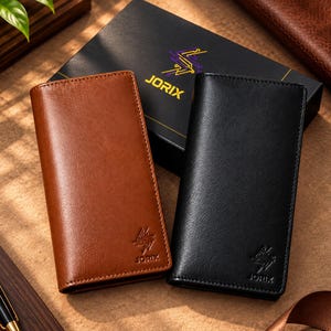 May include: Two rectangular bifold wallets in tan and black leather, each featuring the embossed JORIX logo on the bottom corner. The wallets are positioned in front of a black JORIX branded gift box with gold and purple graphic accents.