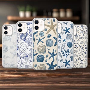 May include: Five clear phone cases with seashell designs. The cases feature illustrations of starfish, shells, and coral in blue and tan. The cases are displayed on a wooden surface.