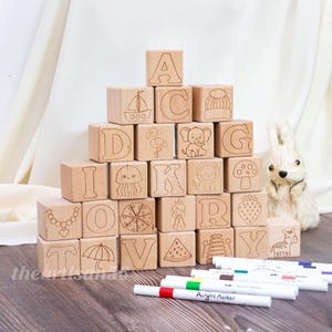 May include: A white ceramic mug with a black handle and the text "But First, Coffee" in a bold, black font. The mug is set against a blurred background, suggesting a cozy setting.