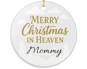 Op de afbeelding: Ronde witte kerstversiering met gouden tekst: "MERRY Christmas IN HEAVEN Mommy". Het heeft een gouden ophangkoord, witte wolken en kerstboom illustraties.