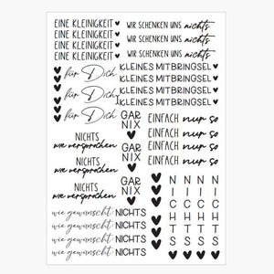 Peut inclure: Une feuille blanche avec du texte noir dans différentes polices. Les phrases incluent "Eine Kleinigkeit", "Wir schenken uns nichts", "für Dich", "Kleines Mitbringsel", "Nichts wie versprochen", et "wie gewünscht: Nichts". Des coeurs noirs sont également présents.