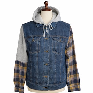 Op de afbeelding: Een spijkerjasje met een grijze hoodie-voering en geruite mouwen. De blauwe spijkerjas heeft vier zakken en is dichtgeknoopt. De mouwen hebben een geel, blauw en paars ruitpatroon.