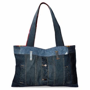 Puede incluir: Un bolso tote de mezclilla con un diseño de patchwork. El bolso está hecho de mezclilla reciclada y presenta un cierre de botón y bolsillos. Las asas están hechas del mismo material de mezclilla y están reforzadas.